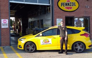 technician and pennzoil car in front of oil change bay